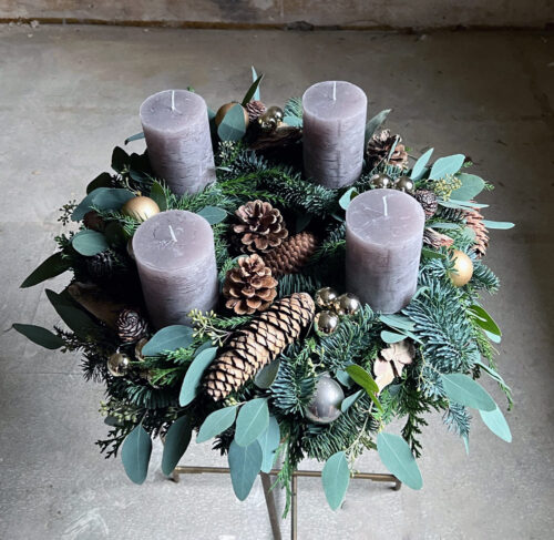 Frischer Adventkranz mit grauen, bräunlich schimmernden Kerzen.